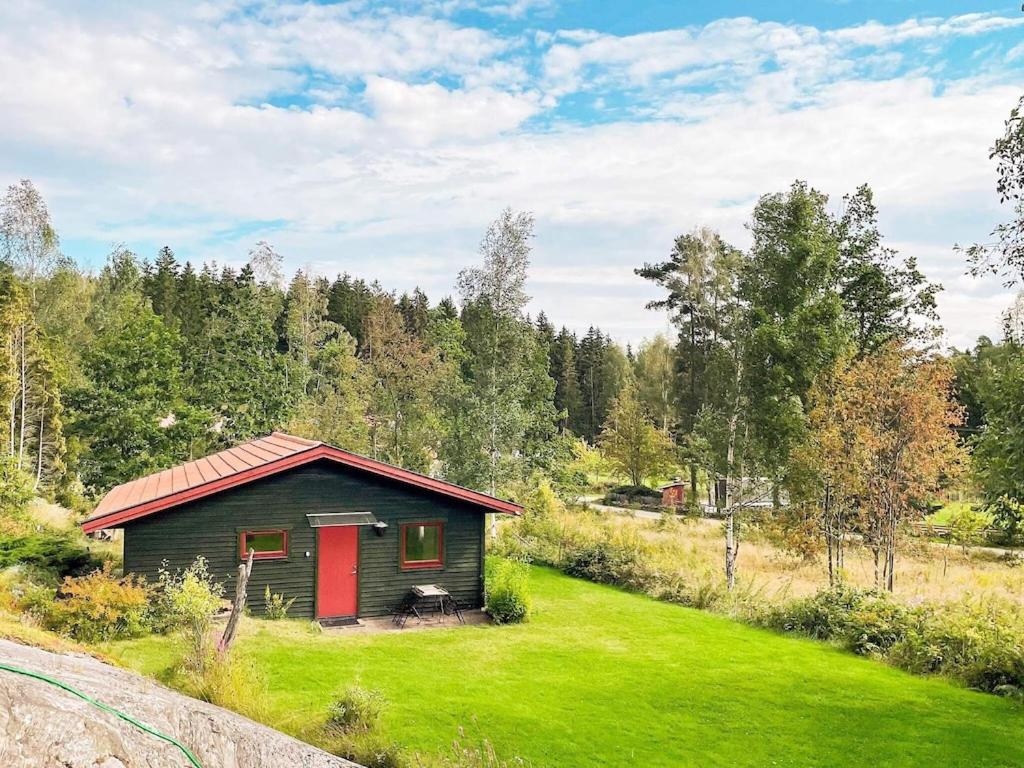 una piccola cabina con una porta rossa in un campo di 3 person holiday home in HEN N a Henån