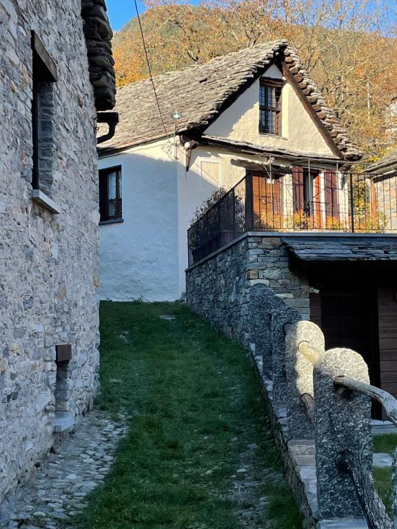 an old stone building with a balcony and a yard at Ul baitin da In Re in Craveggia