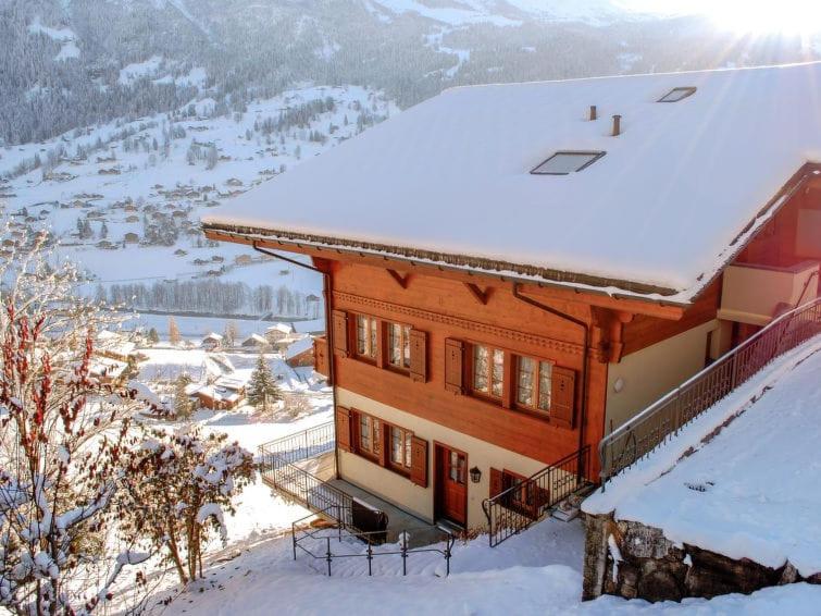 Una casa con nieve en el techo. en Chalet Aphrodite Ost, en Grindelwald