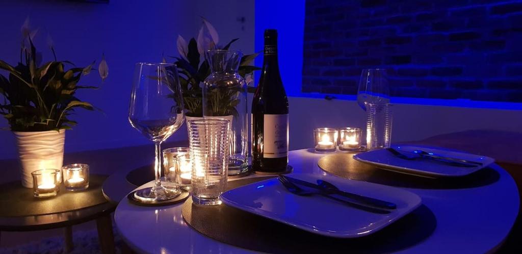 a table with a bottle of wine and glasses and candles at La Clé des Champs - Studio PiscineSPA-Sauna au jardin tropical idyllique et bucolique in Jouarre