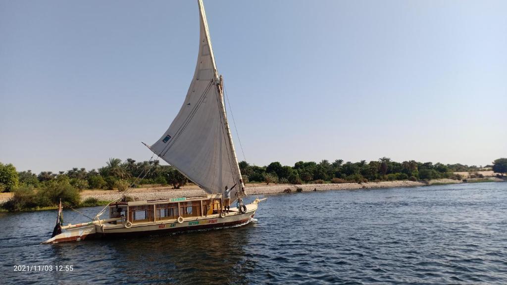 een boot met een groot zeil op het water bij JJ Jamaica Felucca in Aswan