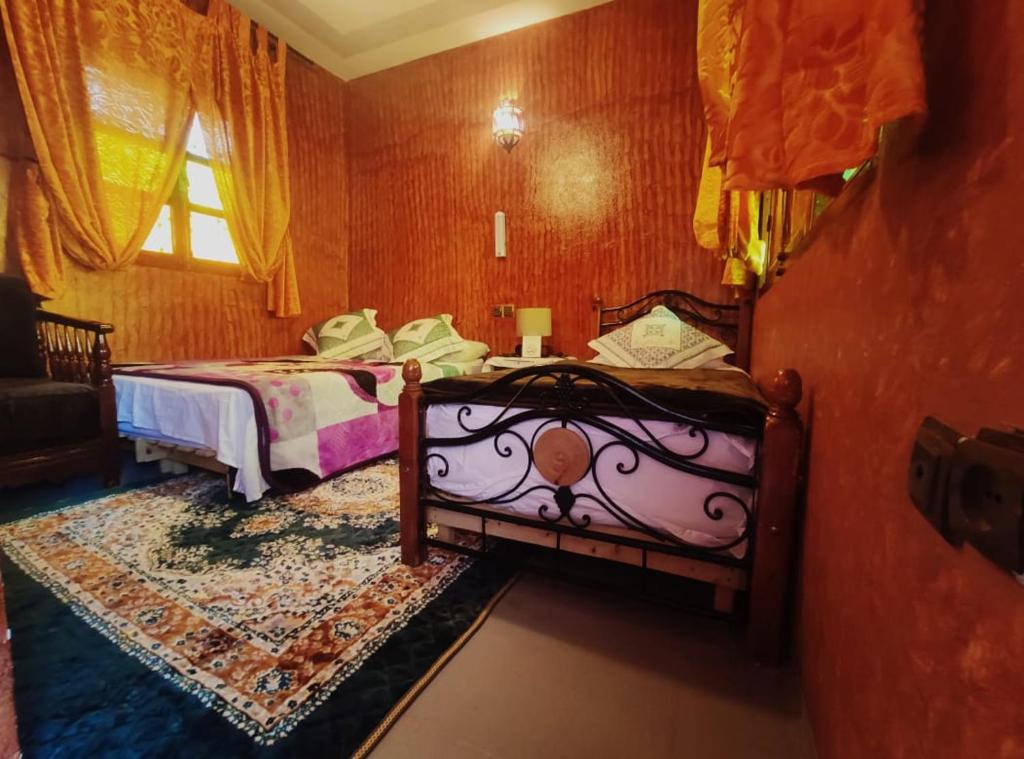 a bedroom with two beds and a window at Kasabah Senhaji in Moulay Idriss Zerhoun