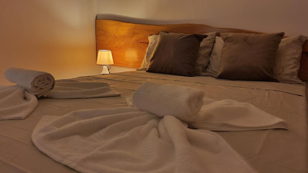 uma cama com lençóis brancos e toalhas em Japaratinga Suites em Japaratinga