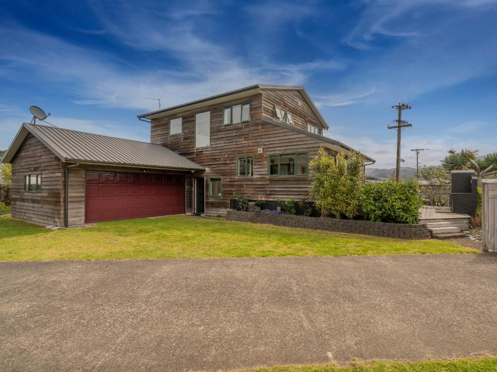 une maison en bois avec un garage en face de celle-ci dans l'établissement Manaia Magic - Tairua Holiday Home, à Tairua