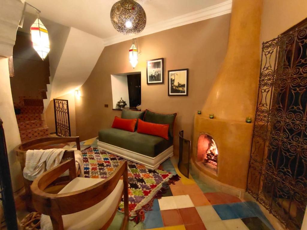 een woonkamer met een bank en een open haard bij Riad BILKIS in Marrakesh