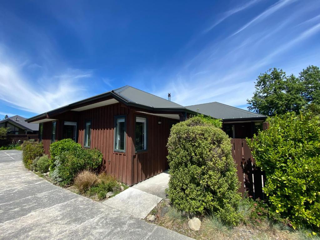 une maison brune avec un toit noir et quelques buissons dans l'établissement 3 Mt Isobel Place, à Hanmer Springs