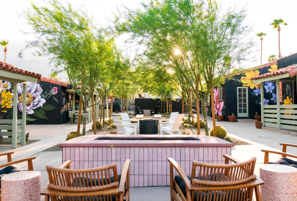 patio con sedie, tavolo e alberi di Fleur Noire Hotel a Palm Springs