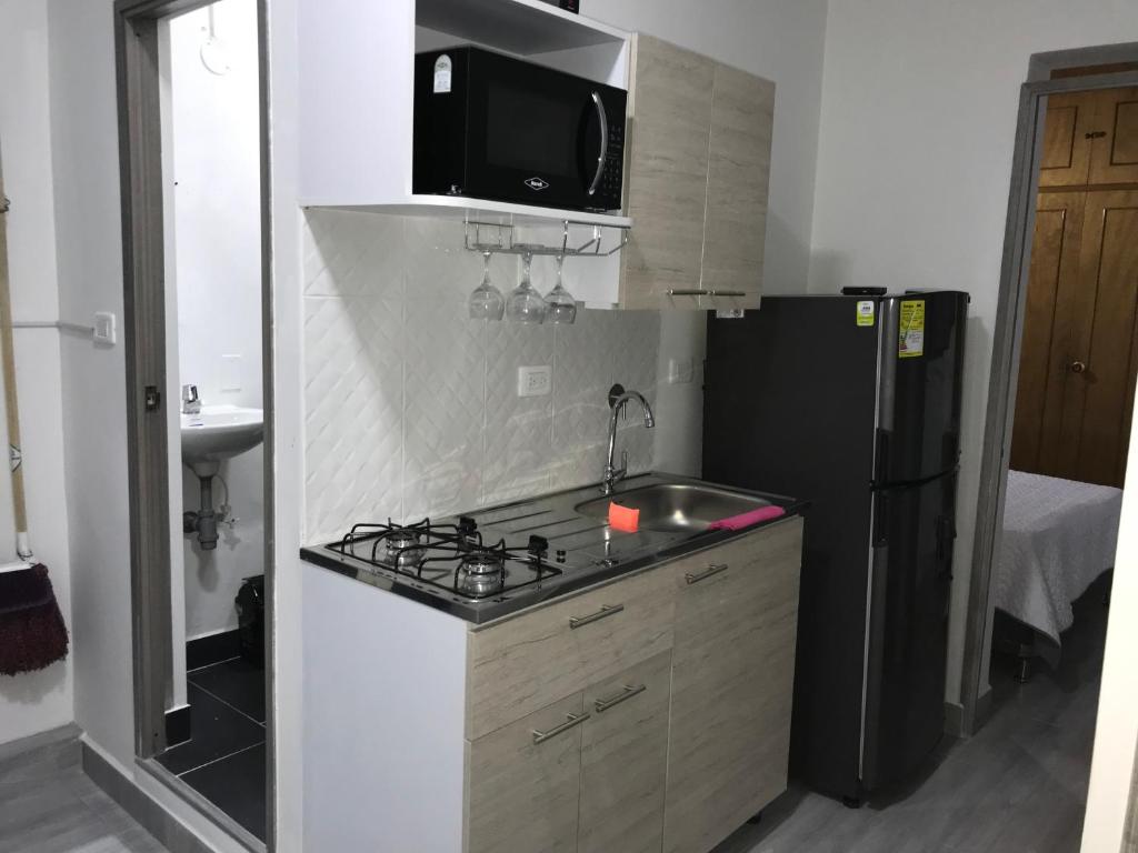 una pequeña cocina con fogones y nevera. en Aparta estudio amoblado 3 Medellin, San joaquin, en Medellín