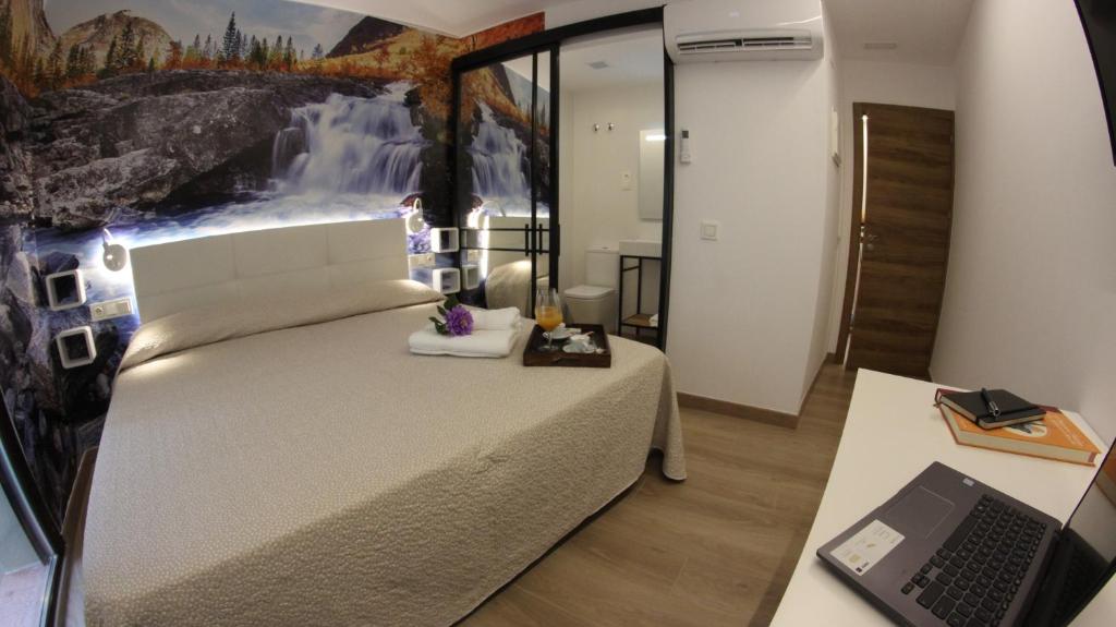 1 dormitorio con cama y escritorio con ordenador portátil en FP HOTELs, en Alcalá de Henares