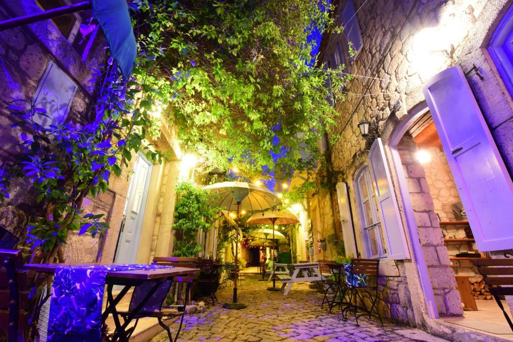 an alley with a table and chairs and an umbrella at Rue d'Azur Alaçatı in Alacati