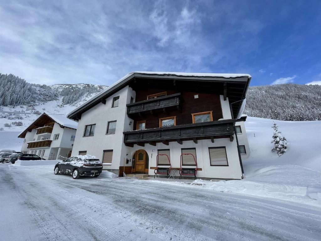 a building with a car parked in the snow at Marlis Apartments in Ischgl
