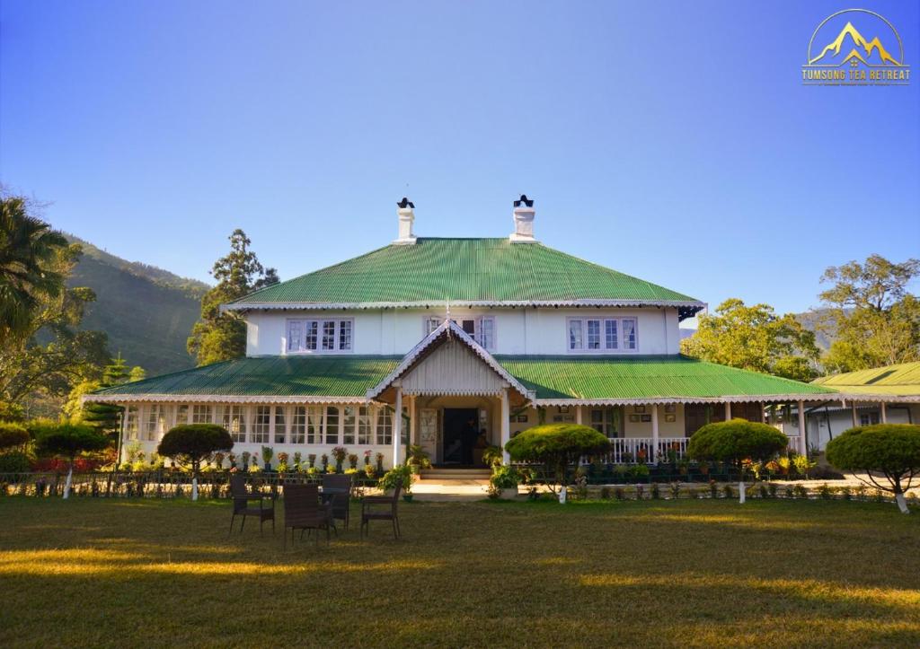 a large white house with a green roof at Tumsong Tea Retreat in Darjeeling