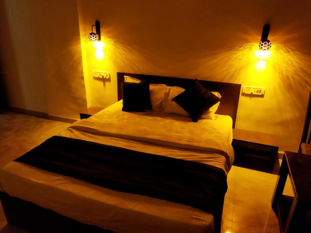 a bedroom with a large bed with two lights at HOTEL RAIN SKY INN in Lonavala