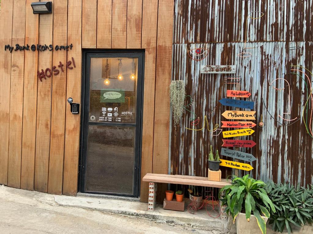 un edificio con una puerta y un banco delante de él en My Bunk Hostel en Ko Samed