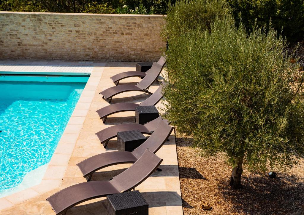 a row of lounge chairs next to a swimming pool at Le Petit Rossignol in Apt