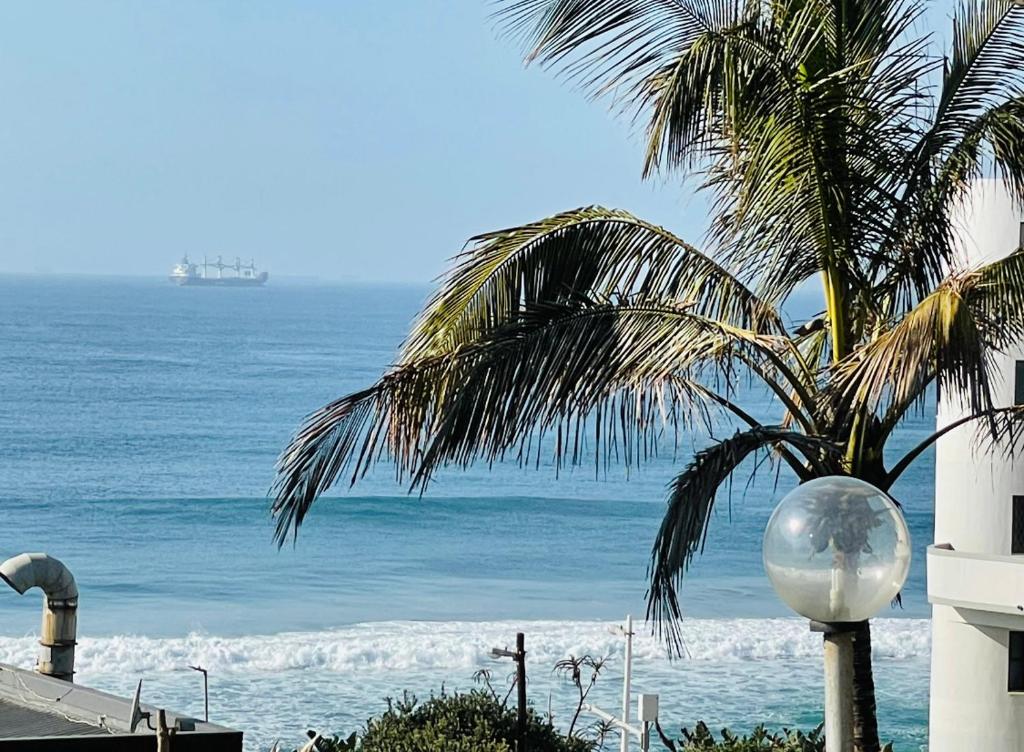 a palm tree with the ocean in the background at M8 Umdloti Holiday Resort in Umdloti