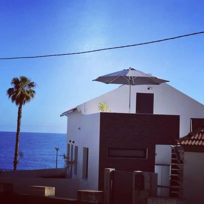 a house with an umbrella on top of it next to the ocean at Lazy Lizard Studio in Seixal