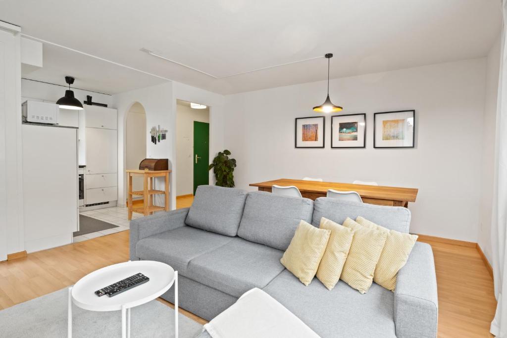 a living room with a gray couch and a table at Bright, Central & Modern apartment in Luzern