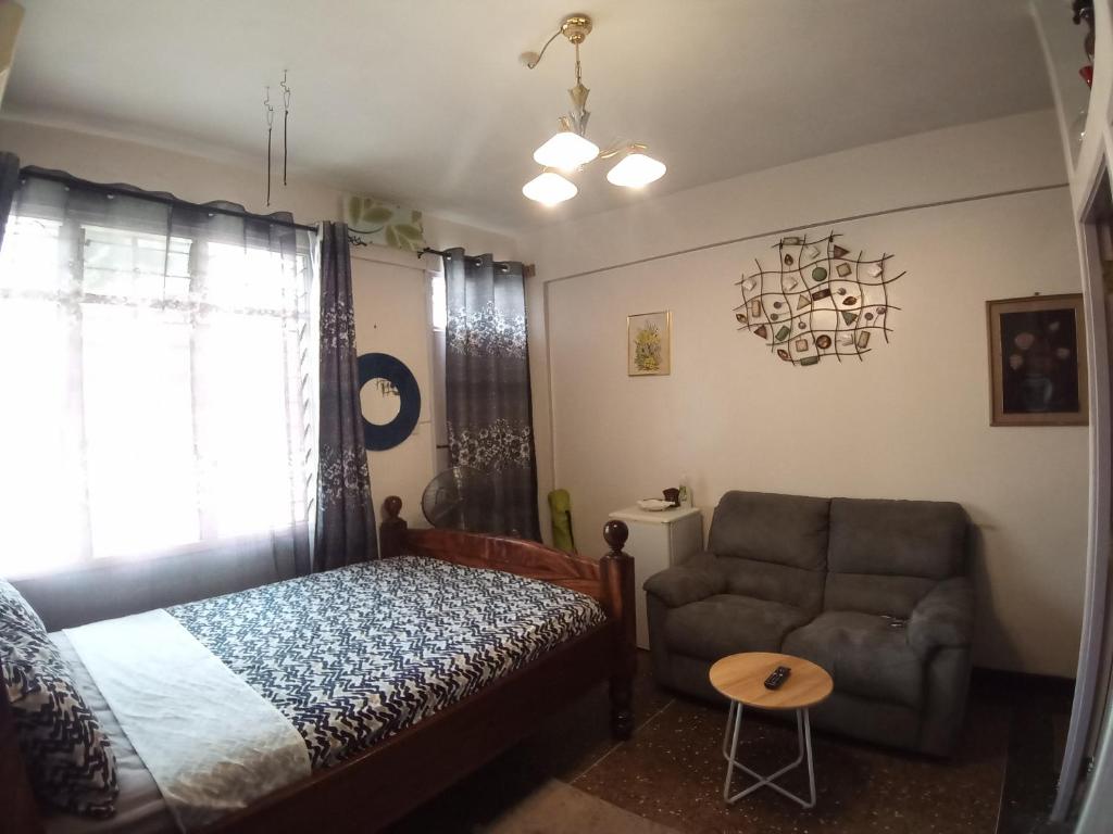 - une chambre avec un lit, un canapé et une chaise dans l'établissement RAFIKI Apartment, à Mombasa