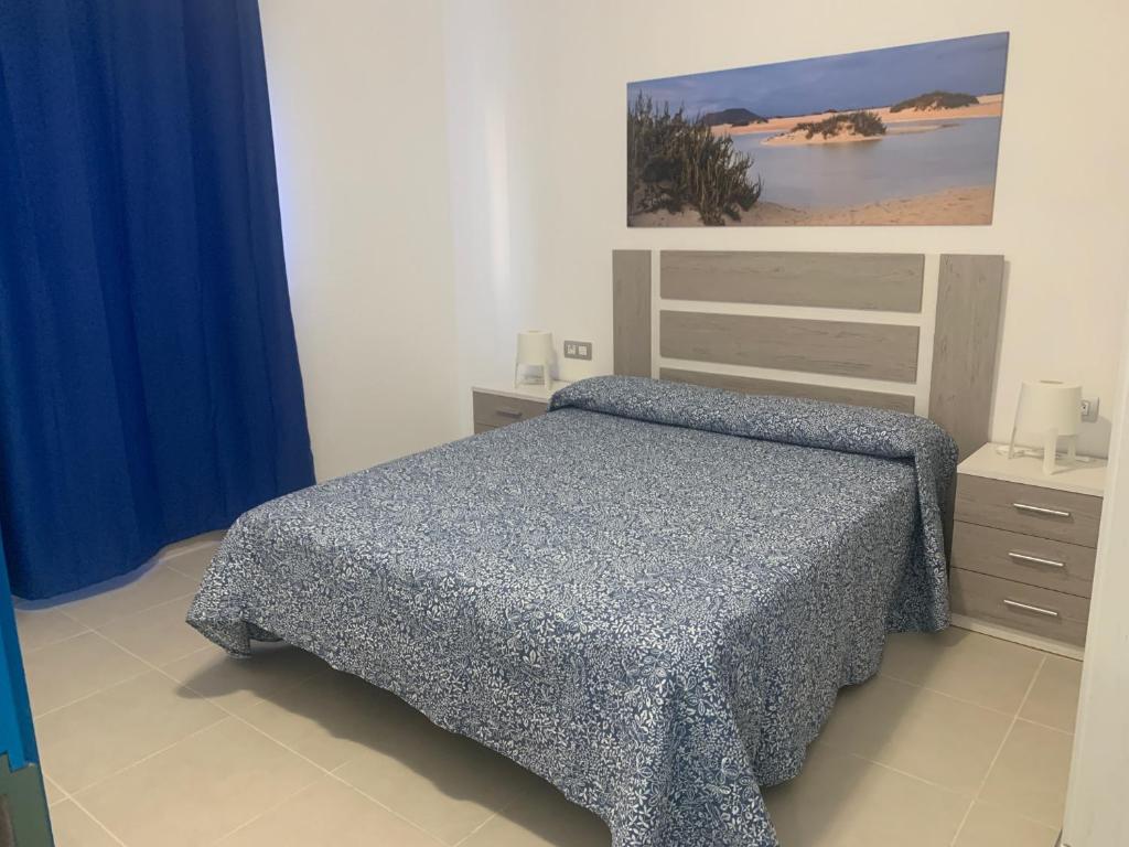 a bedroom with a bed with a blue comforter at Apartamentos Tao Noah in Puerto del Rosario