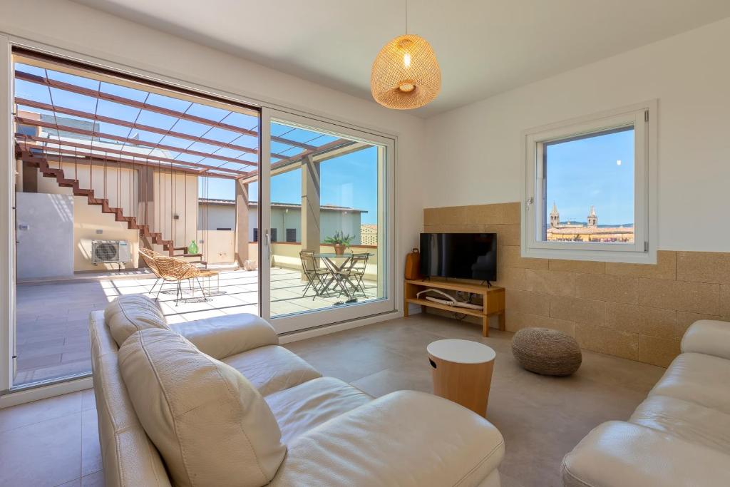 een woonkamer met een bank en een televisie bij Amazing views of Alghero old town and the sea in Alghero
