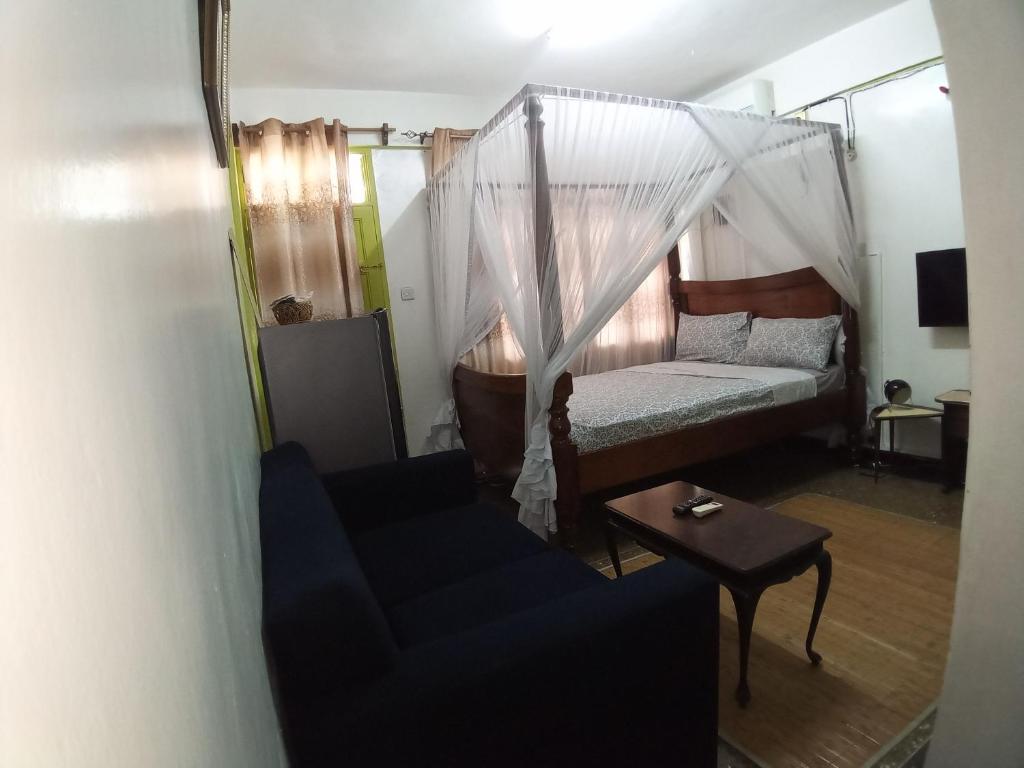 a bedroom with a bed and a couch and a table at SAFI Apartment in Mombasa