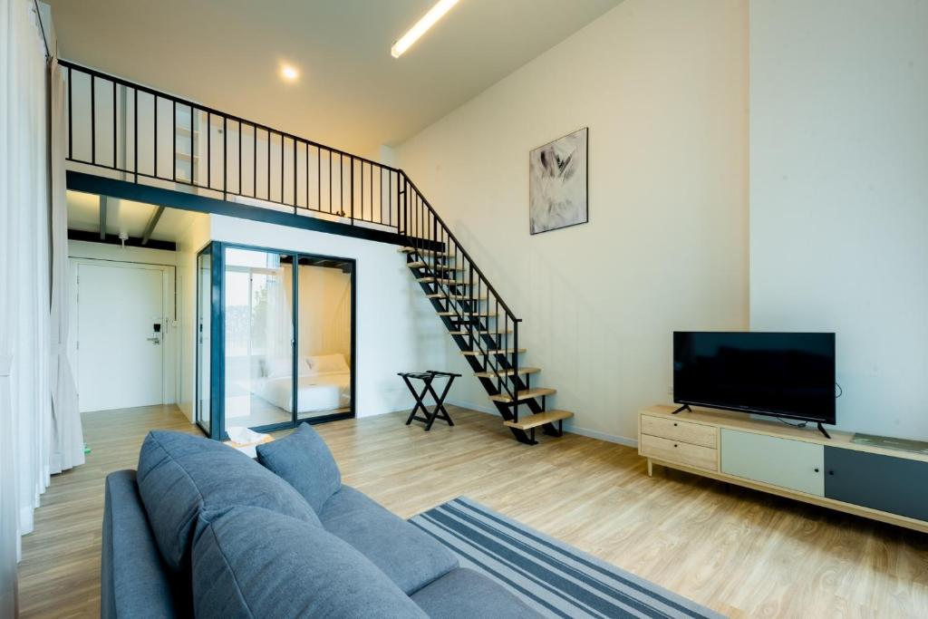 A bright duplex-style living area with a sofa, television and open staircase.