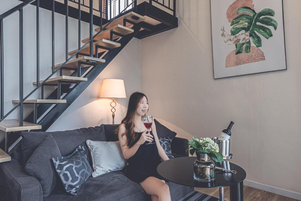 A staged duplex living area with a sofa, wine service and an open staircase.
