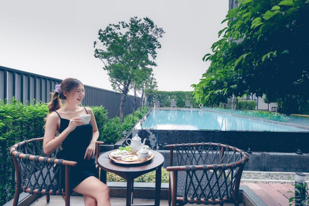 A guest sits with tea beside the outdoor swimming pool.
