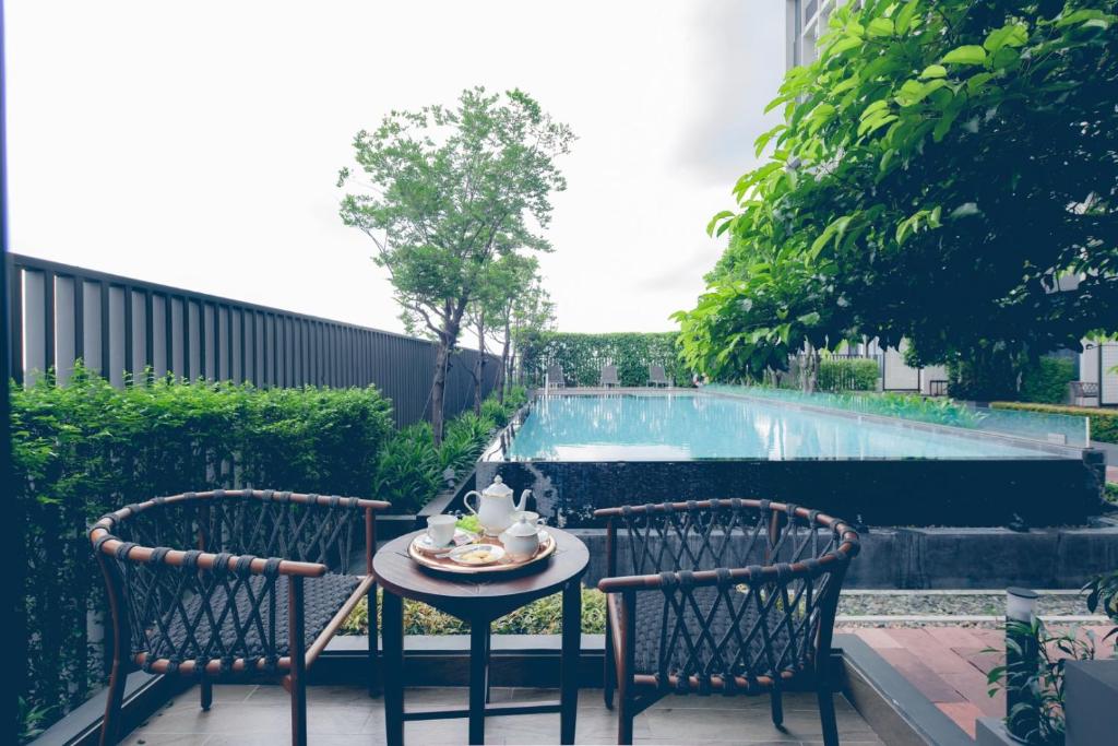 Two outdoor chairs and a small table face the hotel swimming pool.