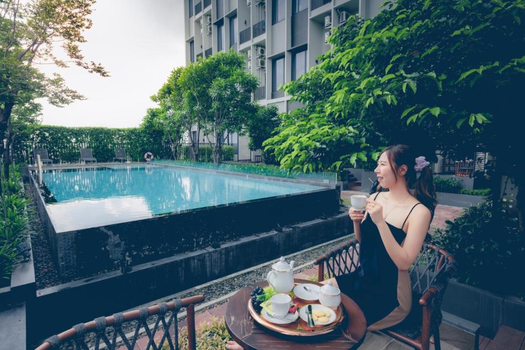 A guest enjoys coffee and a light spread beside the outdoor pool.