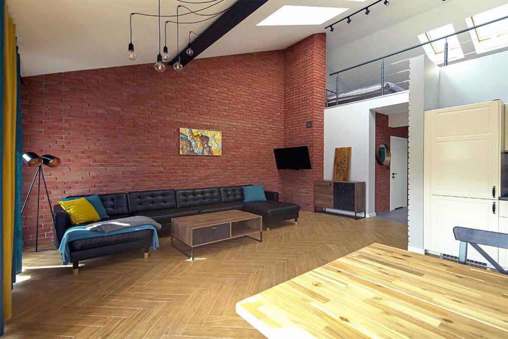 a living room with a couch and a brick wall at Sun&Sport Apartament PANORAMA dwupoziomowy i przestronny in Szczyrk