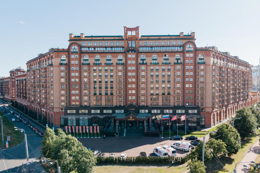 a large brick building with cars parked in front of it at MFK Gornyi Hotel and Congress Centre in Saint Petersburg
