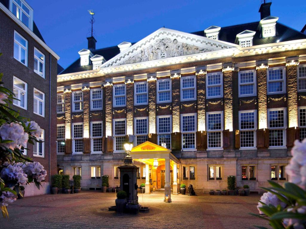 un grand bâtiment avec des lumières devant lui dans l'établissement Sofitel Legend The Grand Amsterdam, à Amsterdam