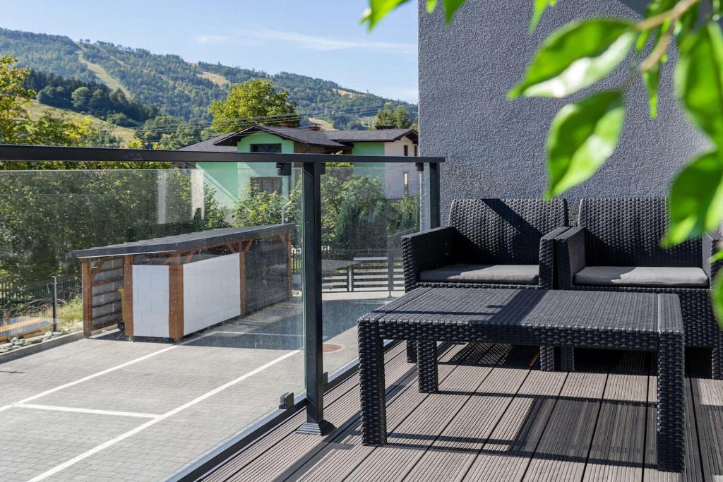 - un balcon avec un banc et une table sur un court de tennis dans l'établissement Sun&Sport Apartament MAJA z ogródkiem, à Szczyrk