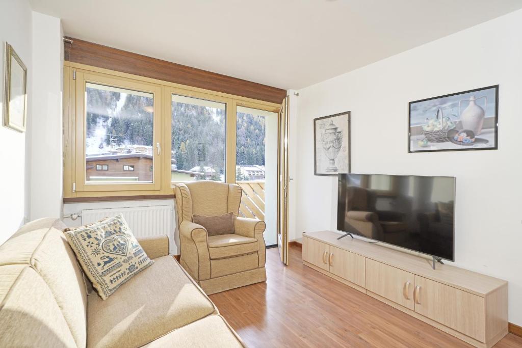a living room with a couch and a flat screen tv at Apartment center Madonna di Campiglio EM in Madonna di Campiglio