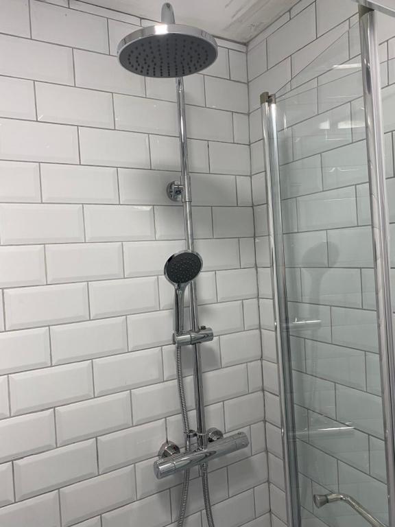 a shower in a bathroom with white tiles at Central Townhouse Whitstable in Whitstable