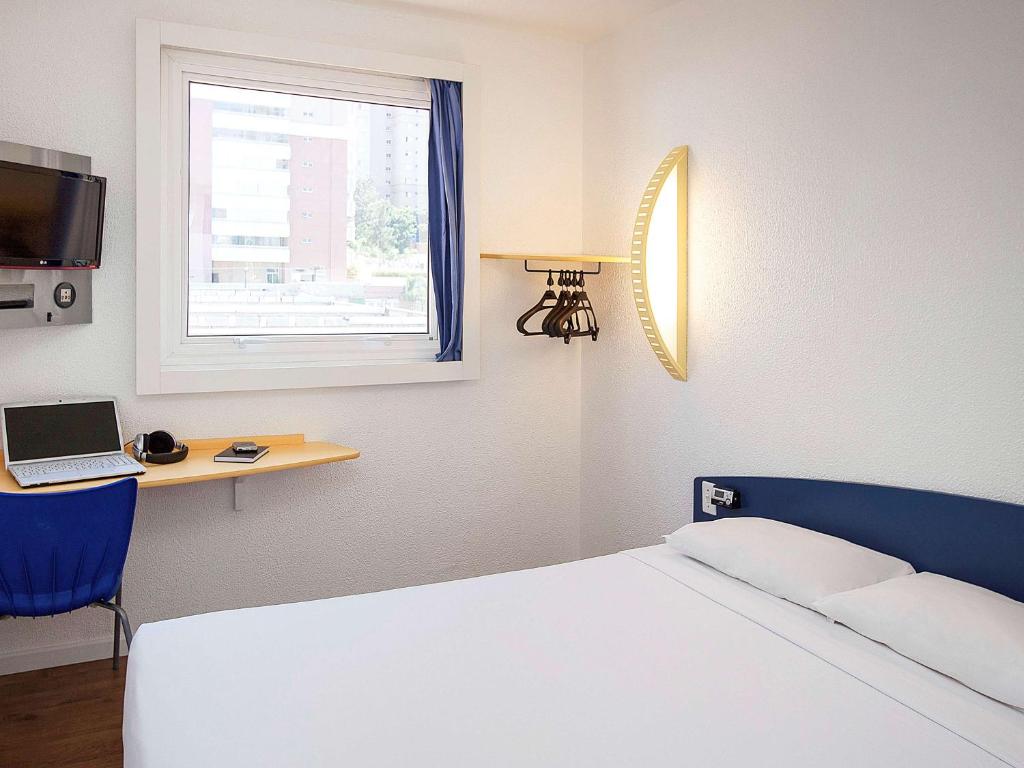 a bedroom with a bed and a desk and a window at ibis budget Sao Paulo Morumbi in Sao Paulo