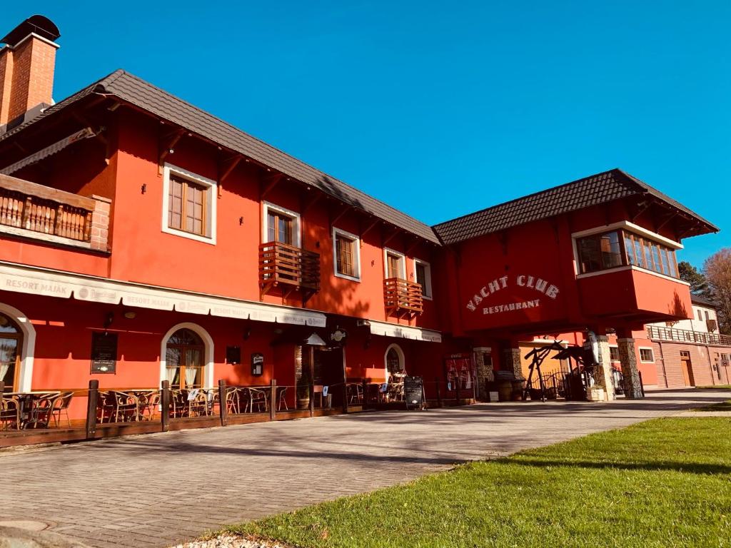 a red building with tables and chairs in front of it at Resort Maják in Horní Soběšovice