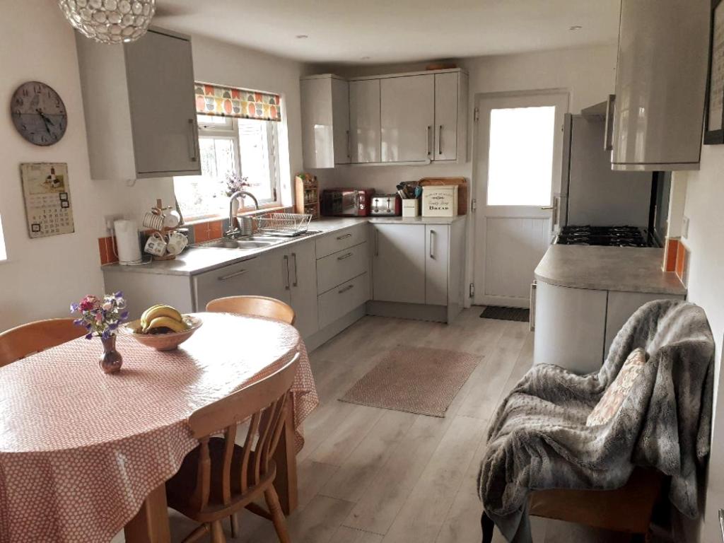 a kitchen with a table and a kitchen with white cabinets at Entire house near beaches, footpaths, dog friendly in Barnstaple