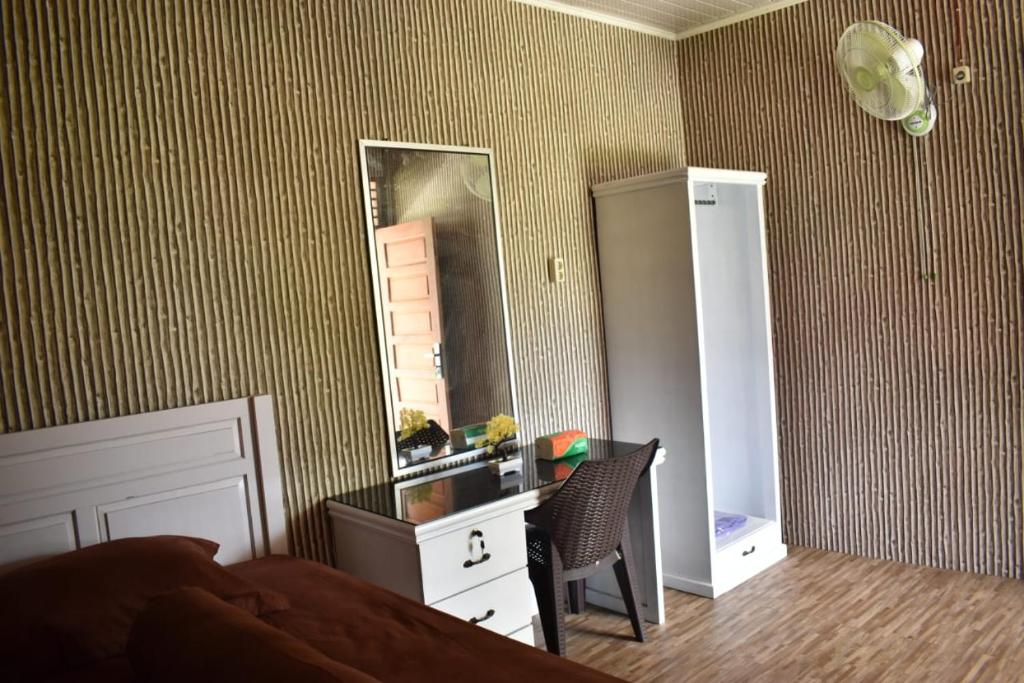Schlafzimmer mit einem Bett, einem Spiegel und einem Schreibtisch in der Unterkunft Pondok Oma III in Lasikin