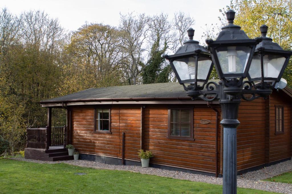 Cabaña de madera pequeña con luz de la calle frente a ella en The Steadings Log Cabins en Kettlebridge