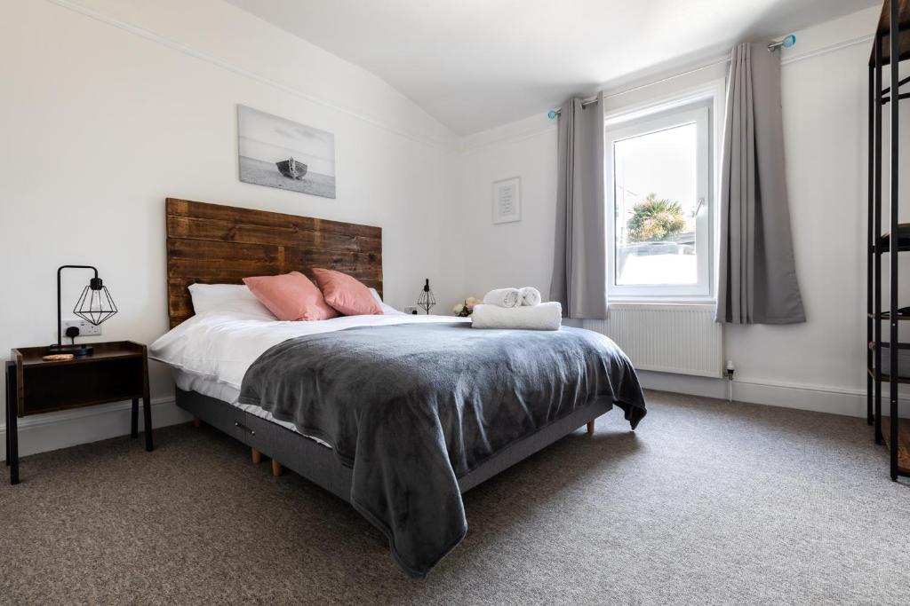 a bedroom with a bed with pink pillows and a window at Falmouth Flat Near Gyllyngvase Beach & Harbour in Falmouth