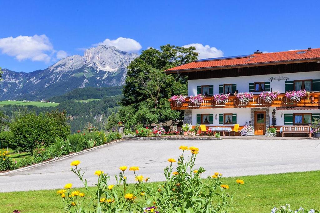 a building with flowers in front of it with mountains at Ferienwohnung Steinlehen in Marktschellenberg