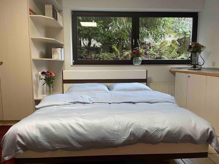 ein Bett in einem Schlafzimmer mit einem großen Fenster in der Unterkunft Schöne ruhige Wohnung (42qm) in Messenähe! in Düsseldorf