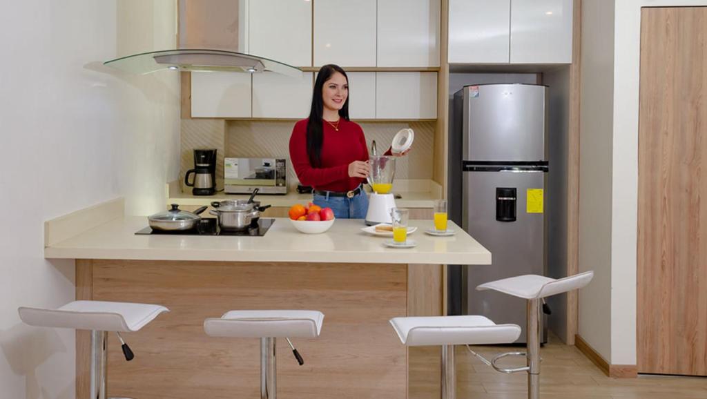 uma mulher numa cozinha com um frigorífico em Hotel Bristo Parc - Apartments & Suites - Centro de Cuenca em Cuenca