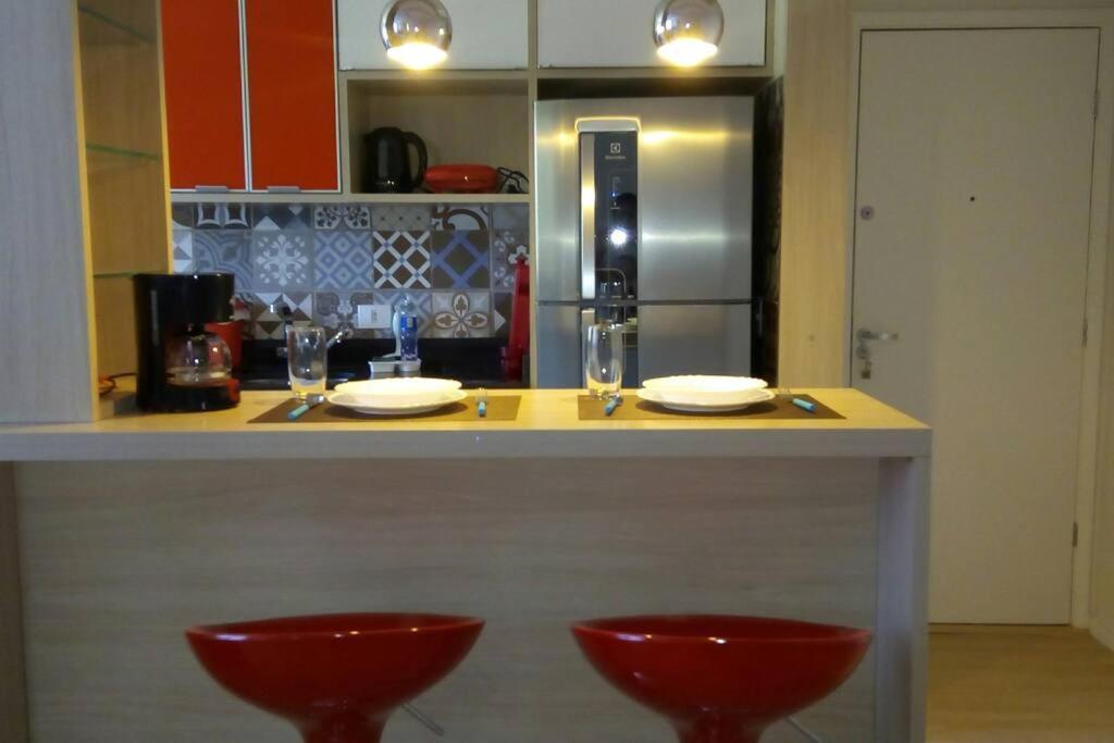 uma cozinha com um balcão com dois bancos vermelhos em Apartamento Lindo e Confortável com 2 quartos e estacionamento grátis Curitiba em Curitiba