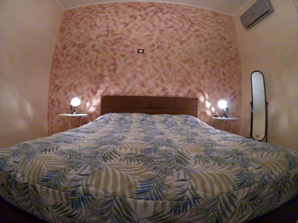 Un dormitorio con una cama grande y una pared rosa en Mamma Loretta' House, en Biancavilla