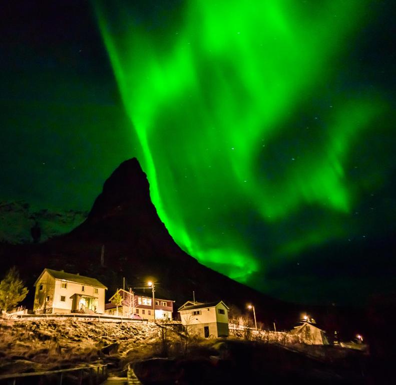 uma imagem da aurora boreal sobre uma cidade em Most photographed house in Reine em Reine