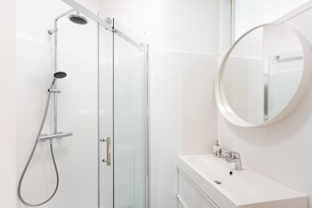 een badkamer met een douche, een wastafel en een spiegel bij Balcony Oasis Operastreet in Wenen
